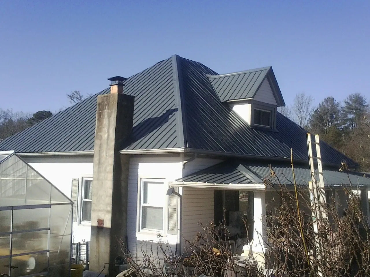 Dark blue standing seam metal roof on a white farmhouse with dormer — Slate & Tile Roof Repair by Roofing Brothers in Mount Union