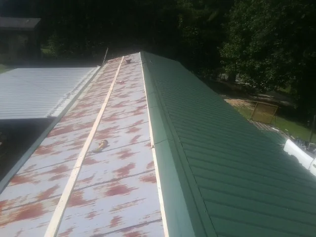 Old rusted panels beside newly installed green metal roofing — Wind Damage Roof Repair by Roofing Brothers in Mount Union