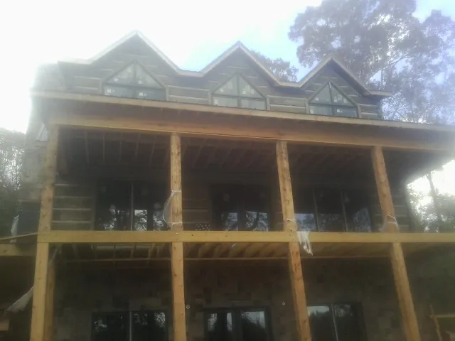 Dormers and porch framing on a large log home under construction — Roof Coating work by our crew in Mount Union