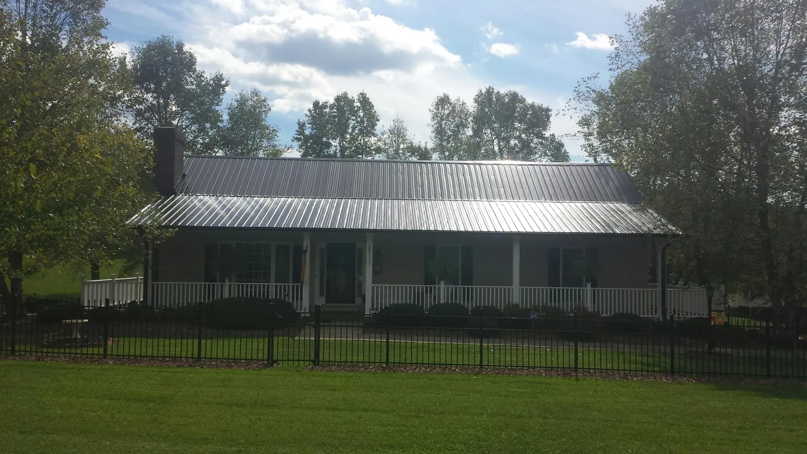 Gray metal roof on a brick ranch with a full width front porch — Gutter Guard Installation work by our crew in Mount Union