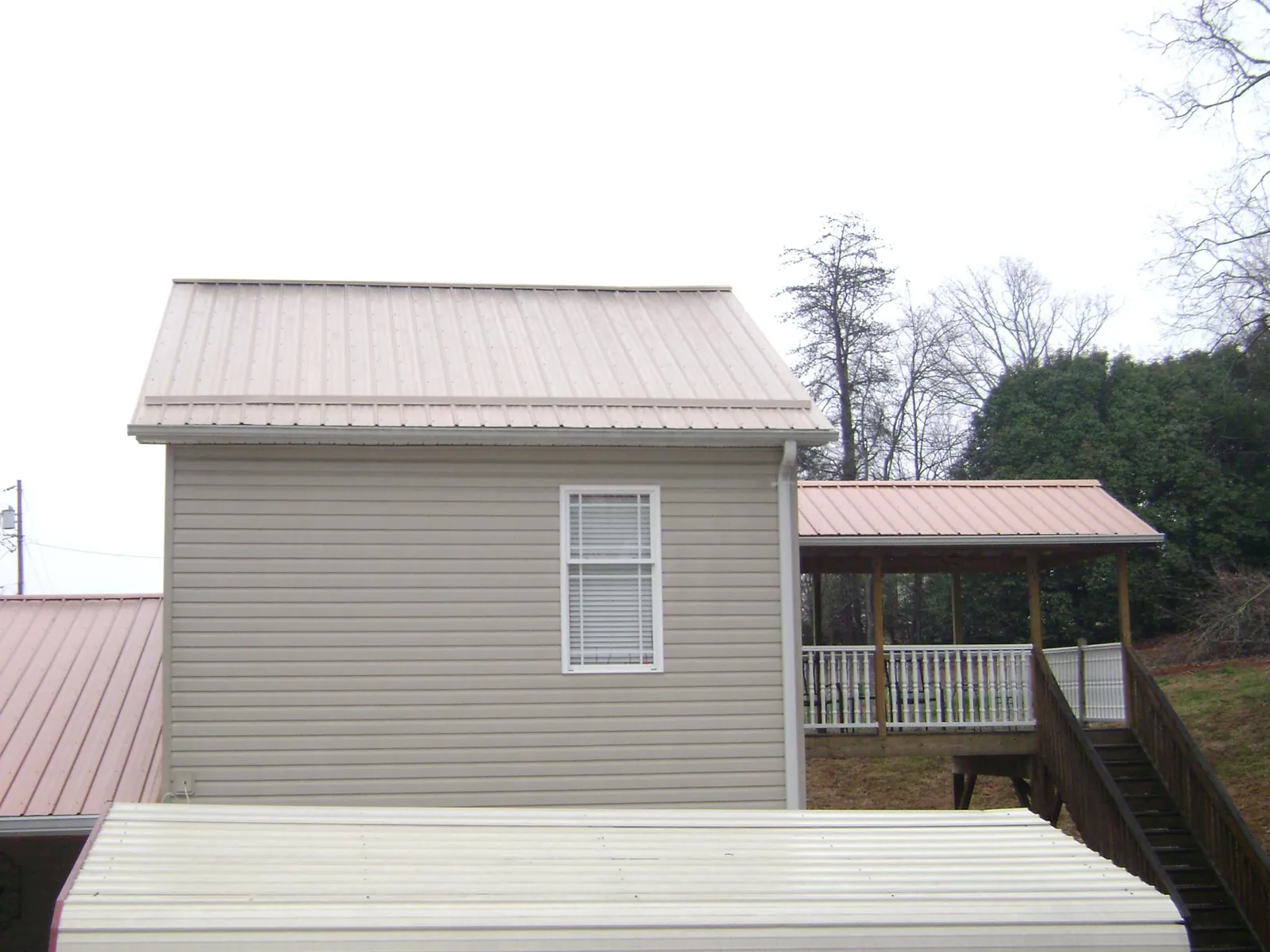 Tan metal roofs on a two story addition and attached porch, from a Roof Replacement job in Mount Union